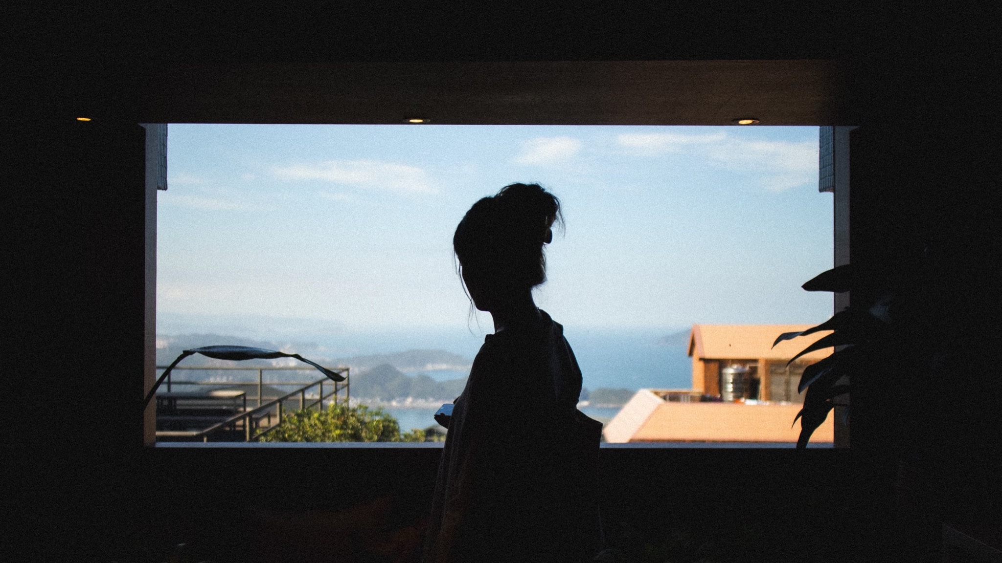 Silhouette against a wide window looking out over a coastal town