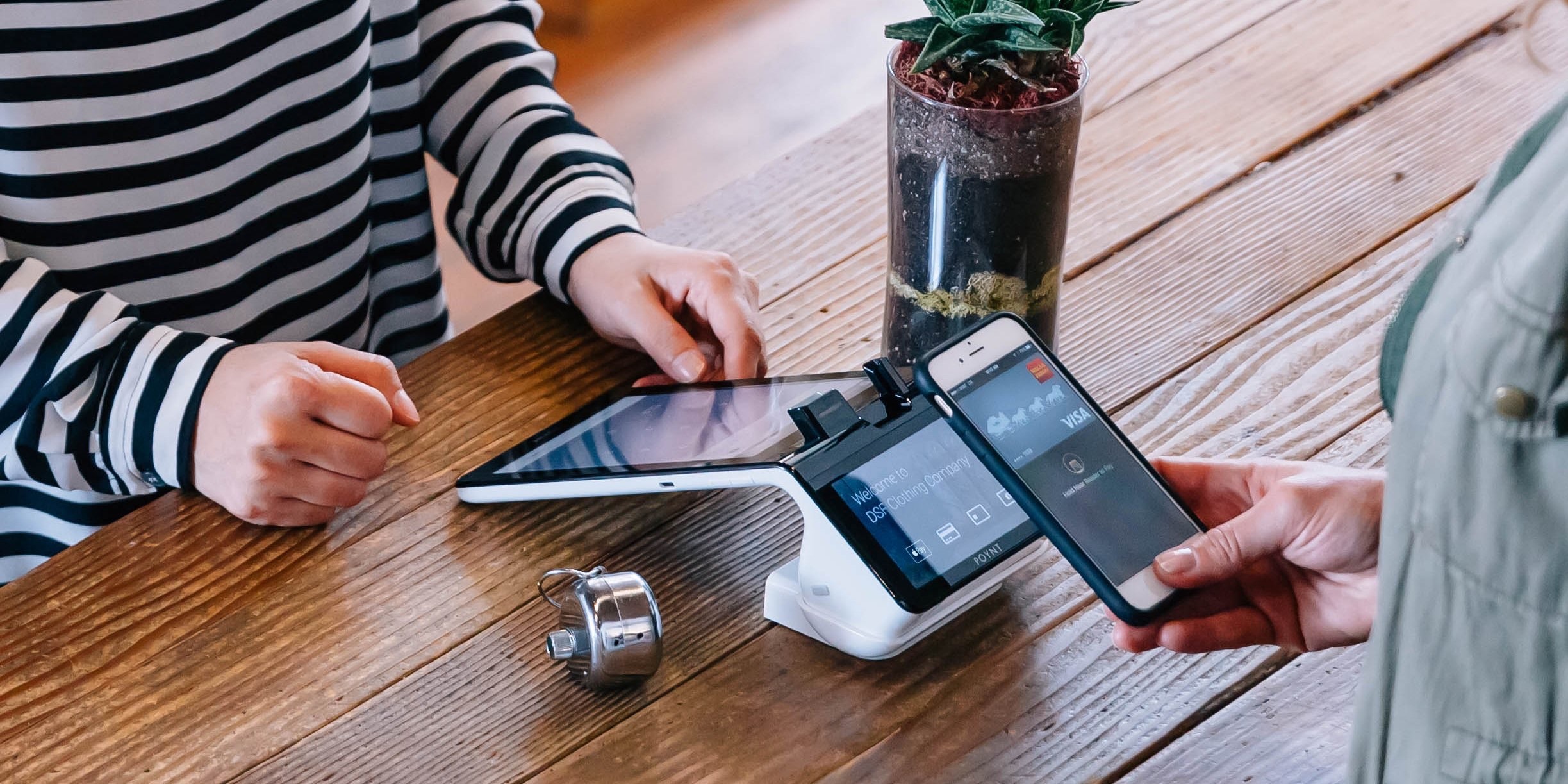 A Poynt terminal on a café counter, a customer paying with a phone
