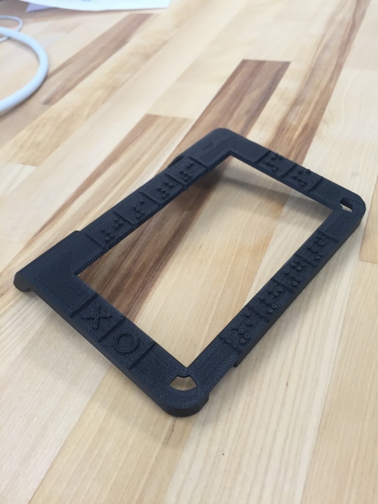 The 3D-printed frame in black plastic, Braille markers moulded into the edges