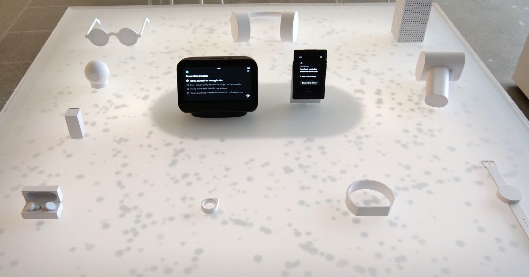 The two working devices on a display table, live and running, among white study models of the other form factors the platform could take